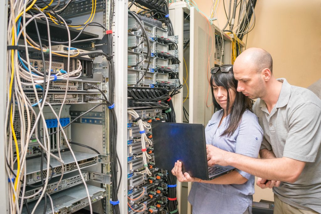 Man and woman set up managed IT services in a server room.