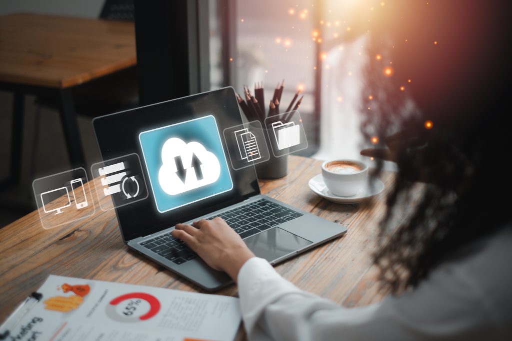 A person working on a laptop with cloud backup icons, symbolizing data security and managed storage solutions in a contemporary office setting.